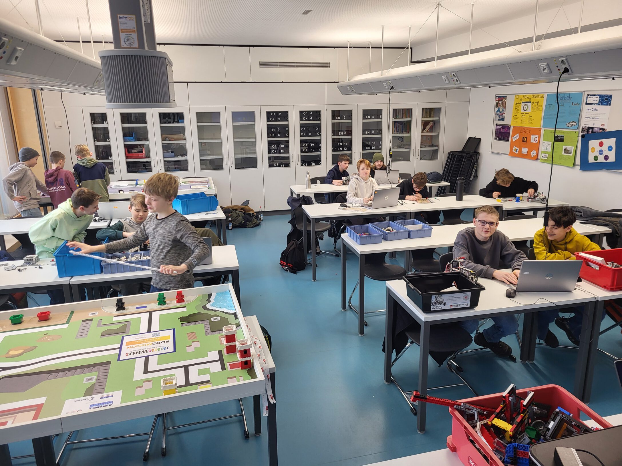 Blick in den Physik-Raum. Zu sehen sind jede Menge Schüler, die an Lego-Robotern bauen.