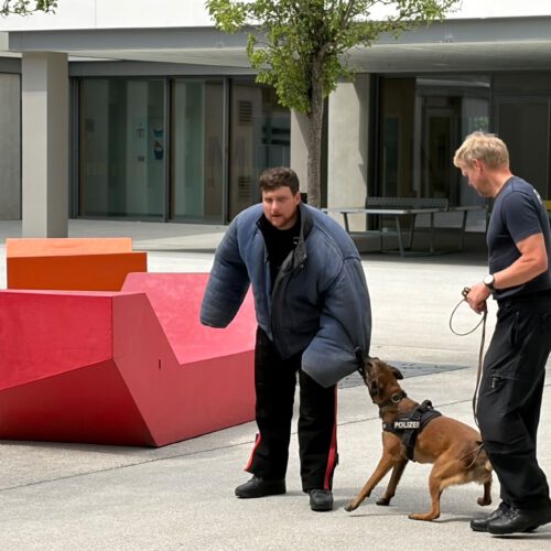 Polizeihauptmeister Florian Eggert (links; verkleidet als Täter einer schweren Straftat), in der Mitte der Polizeihund Mira, Polizeihauptkommissar Uhrmann Wolfgang (rechts)
