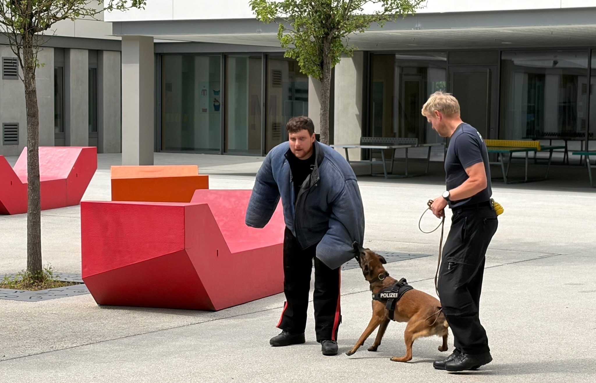 Polizeihauptmeister Florian Eggert (links; verkleidet als Täter einer schweren Straftat), in der Mitte der Polizeihund Mira, Polizeihauptkommissar Uhrmann Wolfgang (rechts)